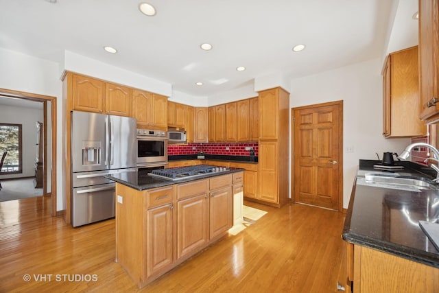 kitchen with stainless steel appliances, dark stone countertops, a center island, and sink