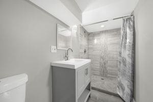 bathroom with a shower with shower curtain, vanity, and toilet