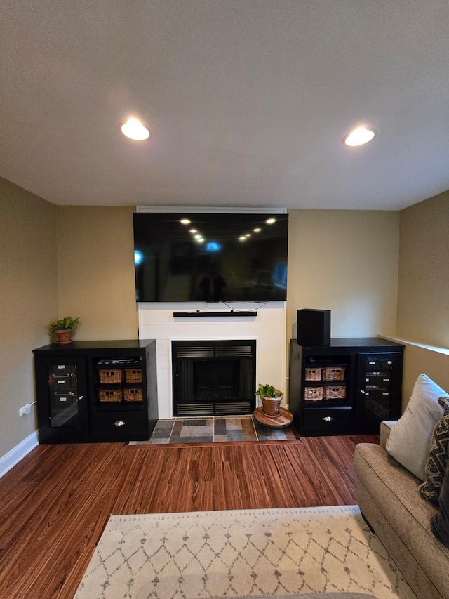 living room with a tiled fireplace and hardwood / wood-style flooring