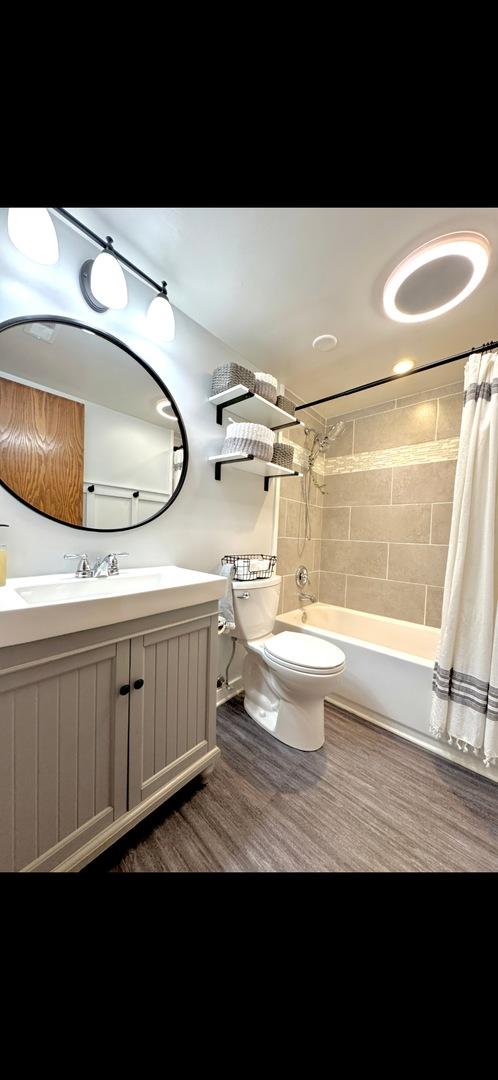 full bathroom featuring hardwood / wood-style floors, vanity, toilet, and shower / bath combo with shower curtain