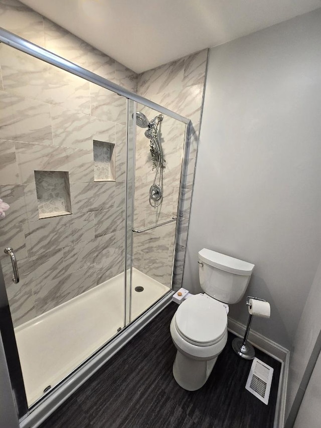 bathroom featuring toilet and a shower with shower door