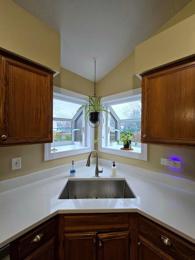 kitchen with hanging light fixtures, plenty of natural light, lofted ceiling, and sink