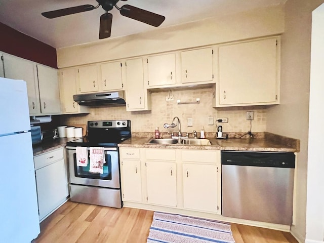 kitchen with tasteful backsplash, sink, stainless steel appliances, and light wood-type flooring