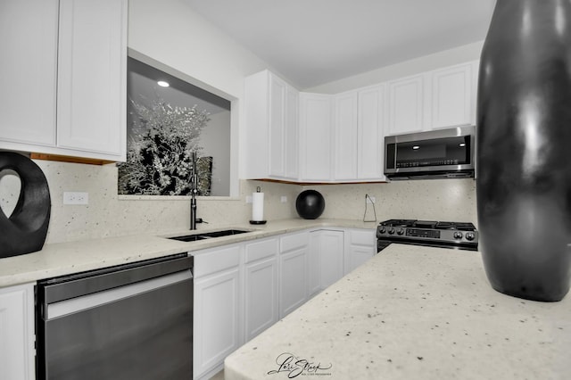 kitchen with light stone countertops, tasteful backsplash, stainless steel appliances, sink, and white cabinetry