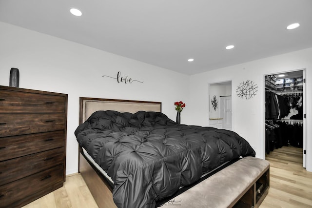 bedroom featuring a walk in closet, light wood-type flooring, and a closet