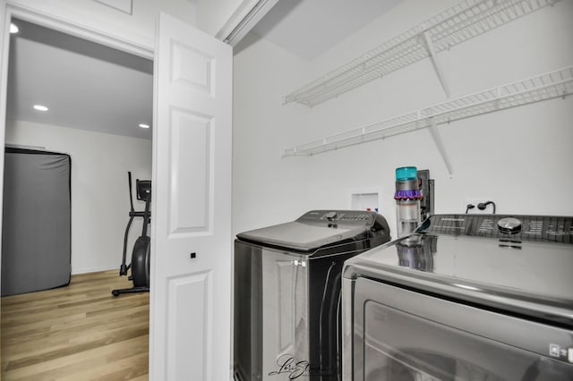 laundry room featuring separate washer and dryer and light hardwood / wood-style floors