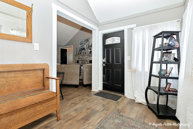 entrance foyer with hardwood / wood-style floors, a fireplace, and vaulted ceiling