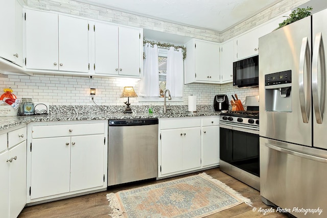 kitchen with wood-type flooring, white cabinetry, and appliances with stainless steel finishes