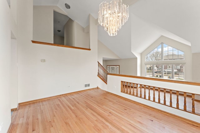 interior space with hardwood / wood-style floors, an inviting chandelier, and high vaulted ceiling