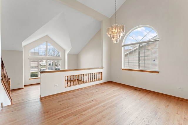 unfurnished living room with an inviting chandelier, light hardwood / wood-style flooring, and lofted ceiling