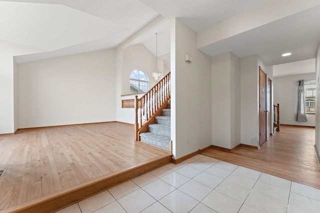 interior space with a chandelier, vaulted ceiling, and light hardwood / wood-style flooring