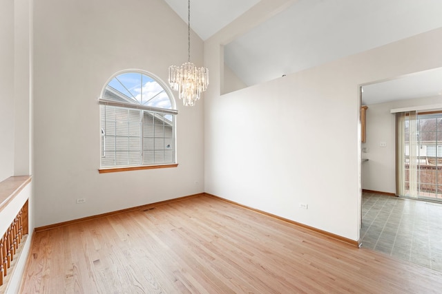 unfurnished room with an inviting chandelier, light hardwood / wood-style floors, and high vaulted ceiling