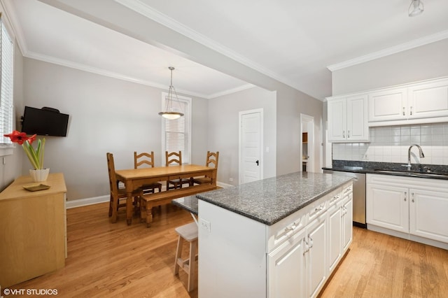 kitchen with a kitchen island, light wood-type flooring, a sink, stainless steel dishwasher, and tasteful backsplash