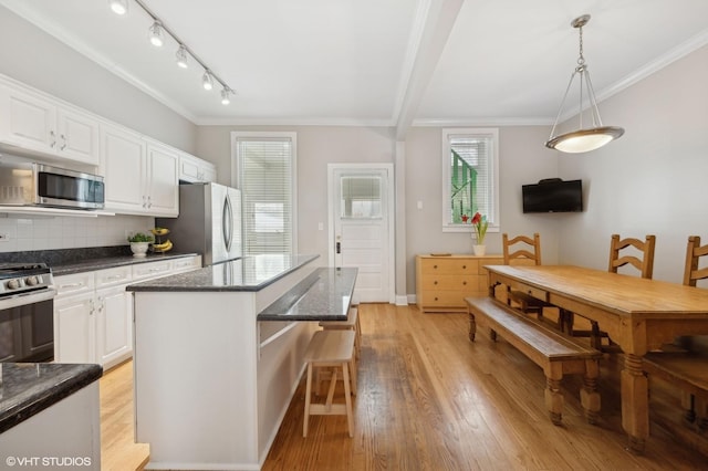 kitchen with light wood-style flooring, white cabinetry, stainless steel appliances, and ornamental molding