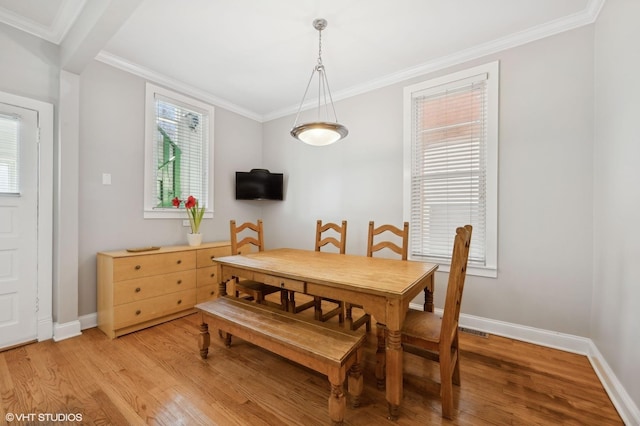 dining space featuring baseboards, light wood finished floors, and ornamental molding