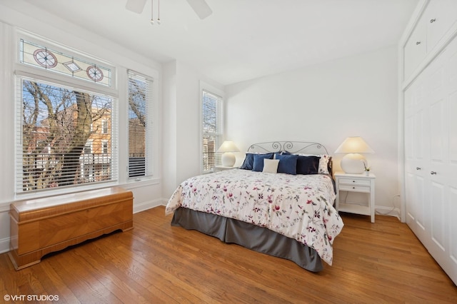 bedroom featuring a closet, ceiling fan, baseboards, and wood finished floors