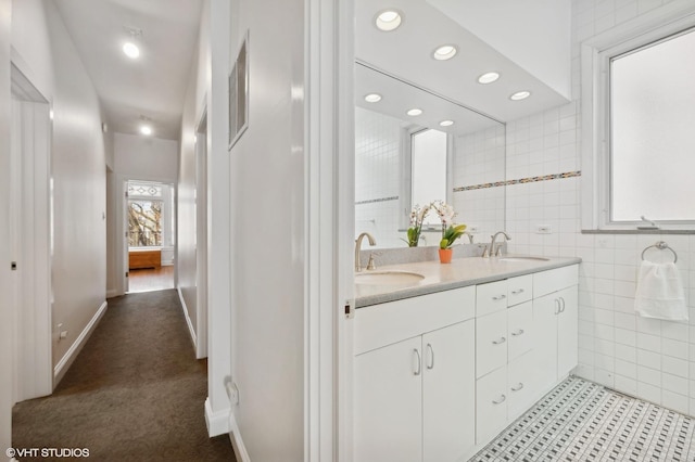 full bath with a sink, tile walls, recessed lighting, and double vanity