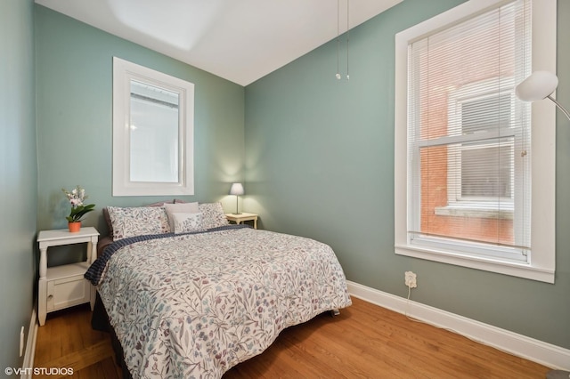 bedroom featuring multiple windows, baseboards, and wood finished floors