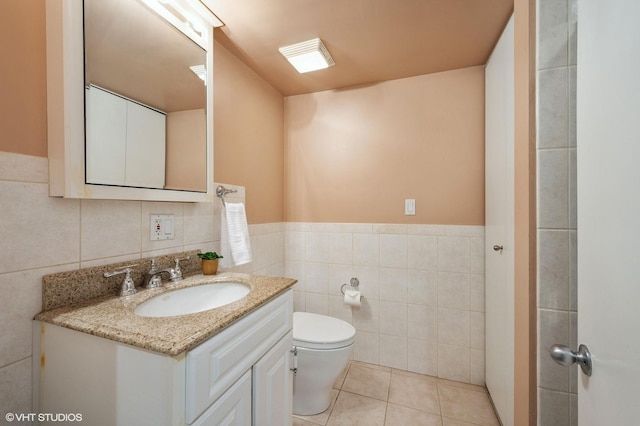 bathroom with vanity, tile patterned flooring, wainscoting, tile walls, and toilet