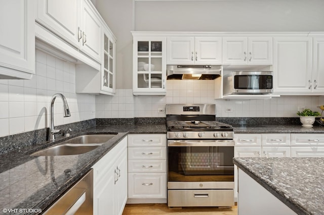 kitchen with under cabinet range hood, appliances with stainless steel finishes, white cabinetry, and a sink