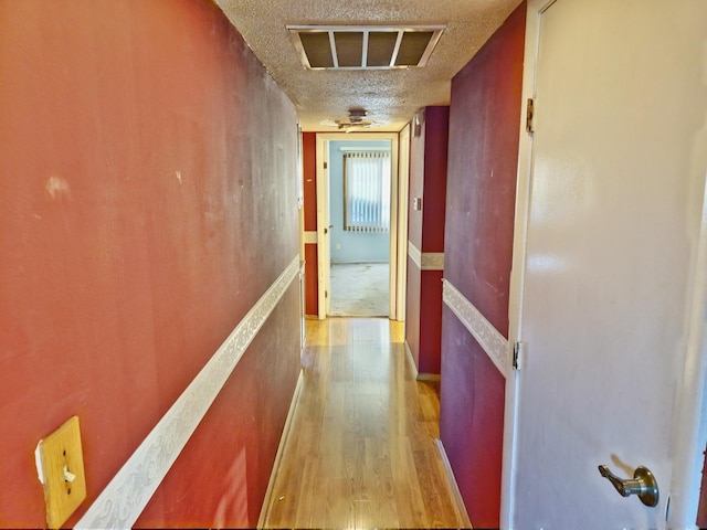 corridor featuring a textured ceiling and light hardwood / wood-style flooring