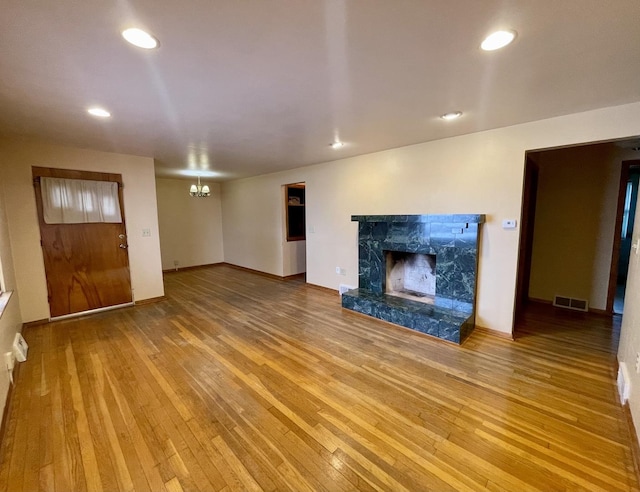 unfurnished living room featuring a chandelier, hardwood / wood-style flooring, and a premium fireplace