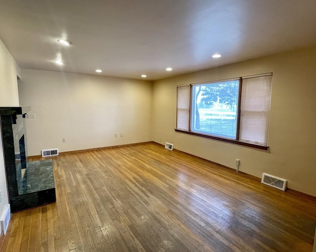 unfurnished living room featuring hardwood / wood-style flooring and a tiled fireplace