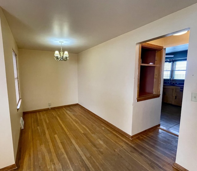 unfurnished room featuring dark hardwood / wood-style flooring and an inviting chandelier