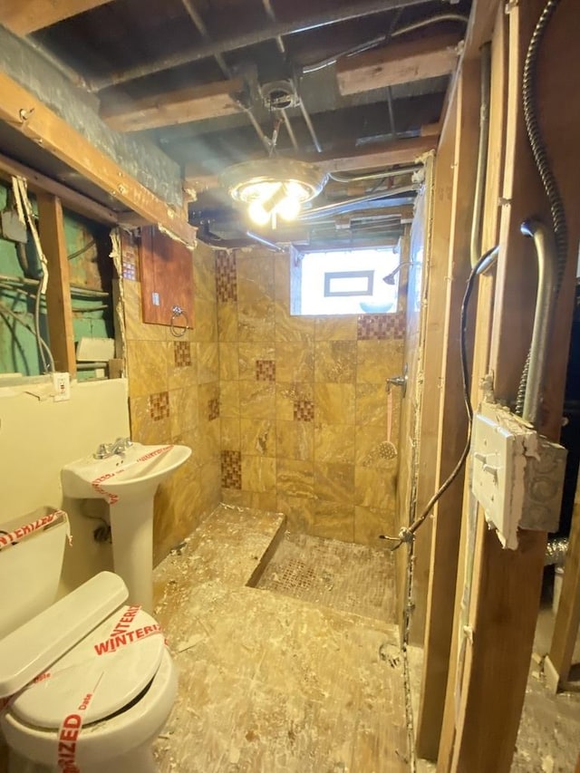 bathroom featuring a tile shower and toilet