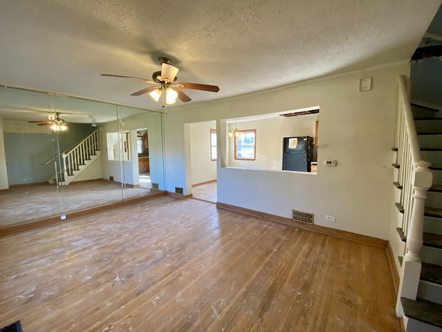 unfurnished living room featuring ceiling fan, wood-type flooring, and a textured ceiling