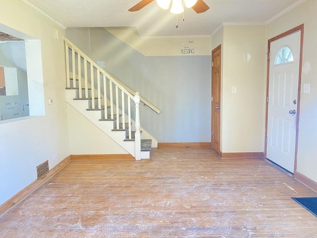 entryway with hardwood / wood-style floors, ceiling fan, ornamental molding, and a textured ceiling