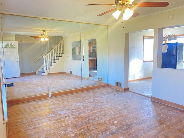 unfurnished room featuring ceiling fan with notable chandelier, crown molding, and light hardwood / wood-style flooring