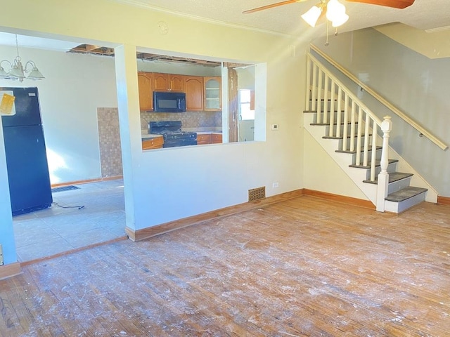 unfurnished living room with ceiling fan with notable chandelier, ornamental molding, and light hardwood / wood-style flooring