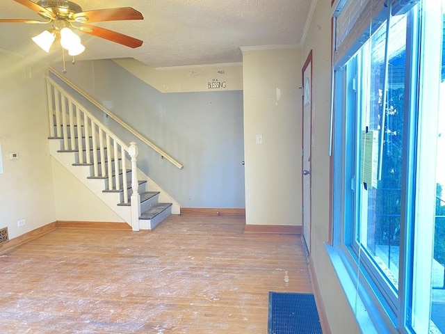 empty room featuring wood-type flooring, a textured ceiling, ceiling fan, and ornamental molding