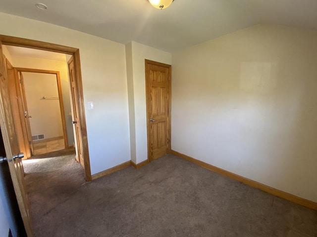 unfurnished bedroom featuring dark carpet and a closet