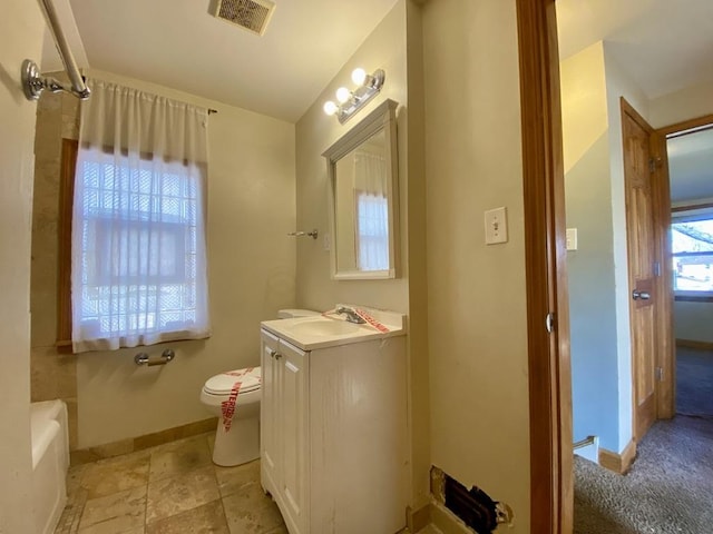 bathroom featuring vanity, toilet, and a tub