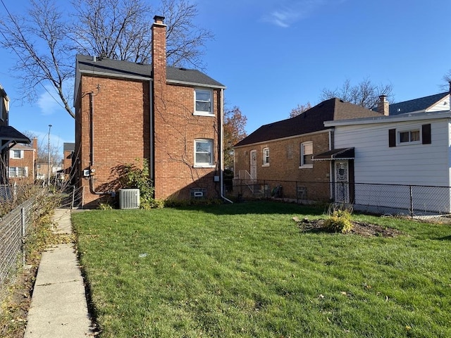 rear view of house with a lawn and central AC unit