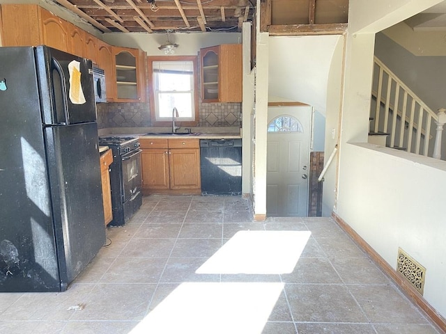 kitchen with decorative backsplash, sink, light tile patterned floors, and black appliances