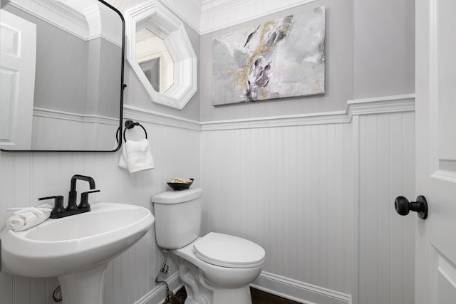 bathroom featuring toilet, ornamental molding, and sink