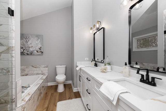 bathroom featuring hardwood / wood-style floors, vanity, toilet, and tiled bath