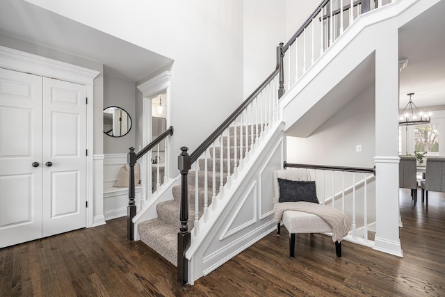 stairway with hardwood / wood-style floors, a high ceiling, and a notable chandelier