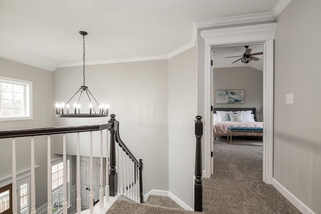 stairway with carpet, ceiling fan with notable chandelier, vaulted ceiling, and ornamental molding