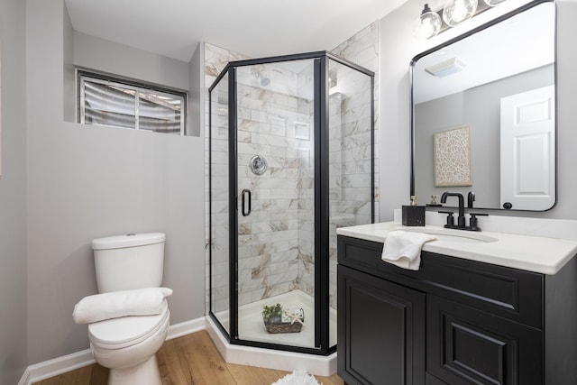 bathroom featuring wood-type flooring, vanity, toilet, and walk in shower