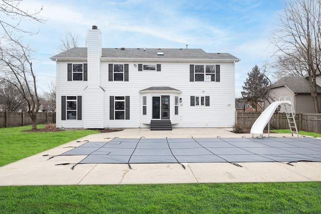 rear view of property with a covered pool, a patio area, and a lawn