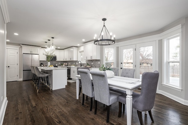 dining space featuring sink, a healthy amount of sunlight, dark hardwood / wood-style floors, and an inviting chandelier