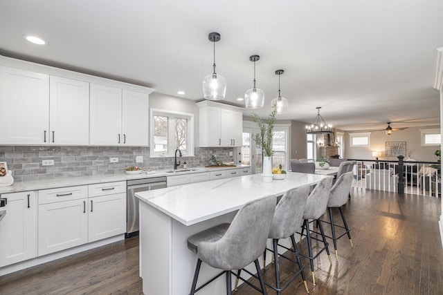 kitchen with a wealth of natural light, dishwasher, white cabinets, and ceiling fan with notable chandelier