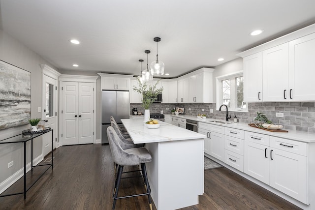 kitchen featuring dark wood-type flooring, sink, white cabinets, a center island, and hanging light fixtures