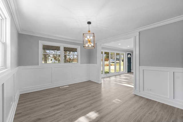 unfurnished dining area featuring a chandelier, hardwood / wood-style flooring, and ornamental molding