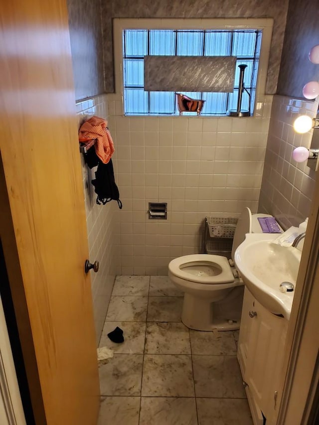 bathroom with vanity, toilet, tile walls, and a wealth of natural light