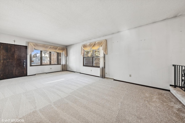 empty room with light colored carpet and a textured ceiling